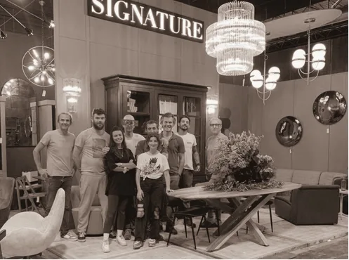 The Signature team gathered on its trade fair stand, in front of a solid oak dresser and beneath its chandeliers